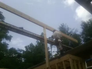 Carpenter setting a ridge beam over a new addition frame — Ice Dam Removal by Roofing Brothers in Black River