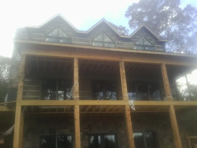 Dormers and porch framing on a large log home under construction — Roof Coating work by our crew in Black River