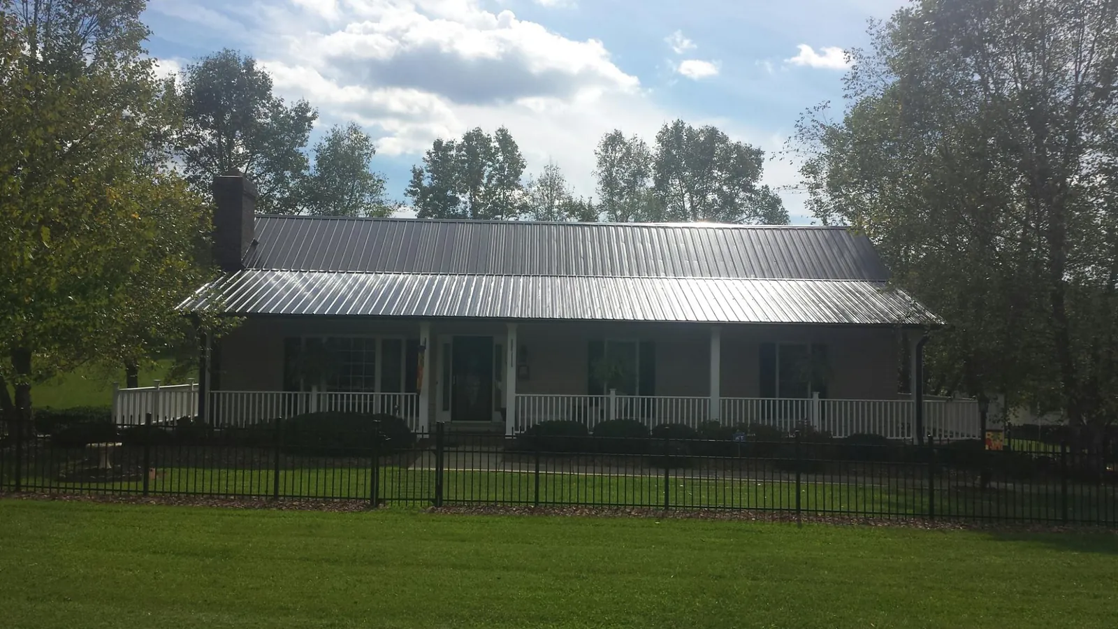 Gray metal roof on a brick ranch with a full width front porch — Gutter Guard Installation work by our crew in Black River
