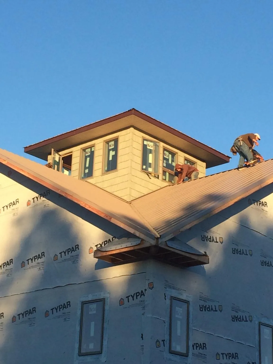 Roofers working around a rooftop cupola on a new metal roof at sunset — Roof Waterproofing in Black River by Roofing Brothers